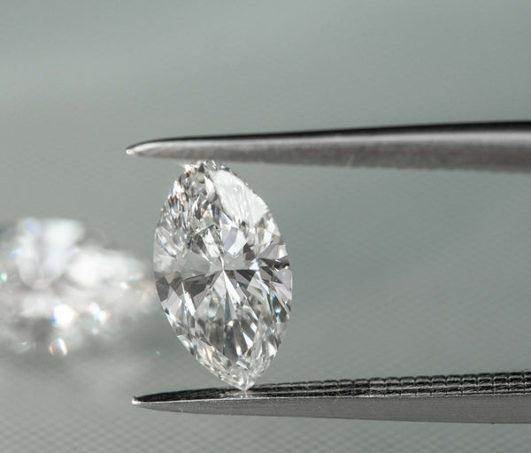 A lab-grown marquise diamond held by tweezers