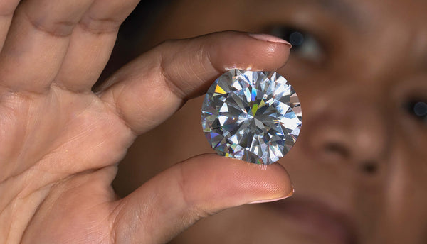 Woman holds up large round-cut diamond to the light