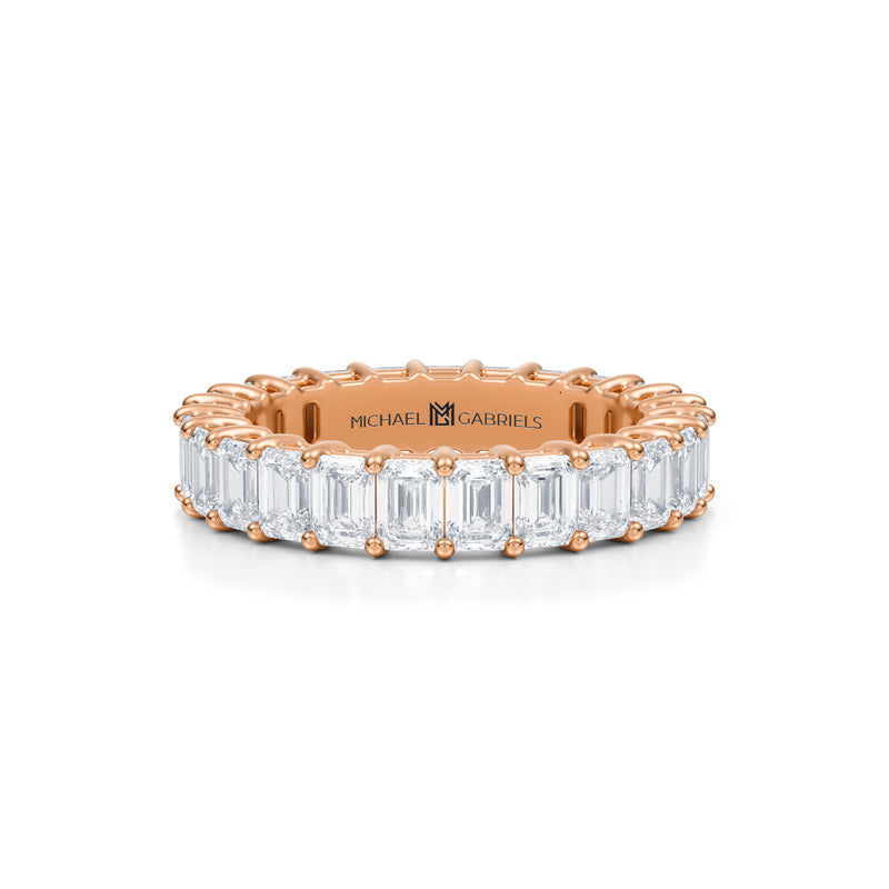 Rose gold eternity band with emerald lab-grown diamonds.
