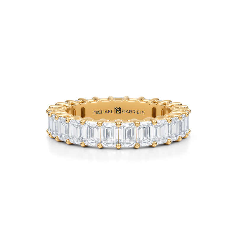 Petite lab-grown diamond eternity band with emerald stones in yellow gold.